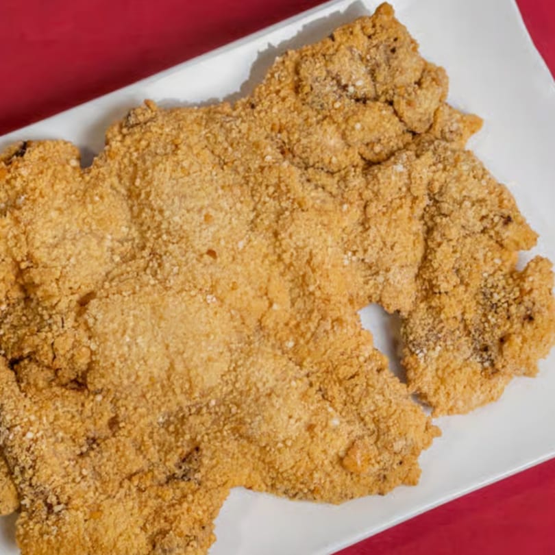 Crispy, golden-brown Taiwanese fried chicken cutlet, sprinkled with seasoning, on a white rectangular plate.